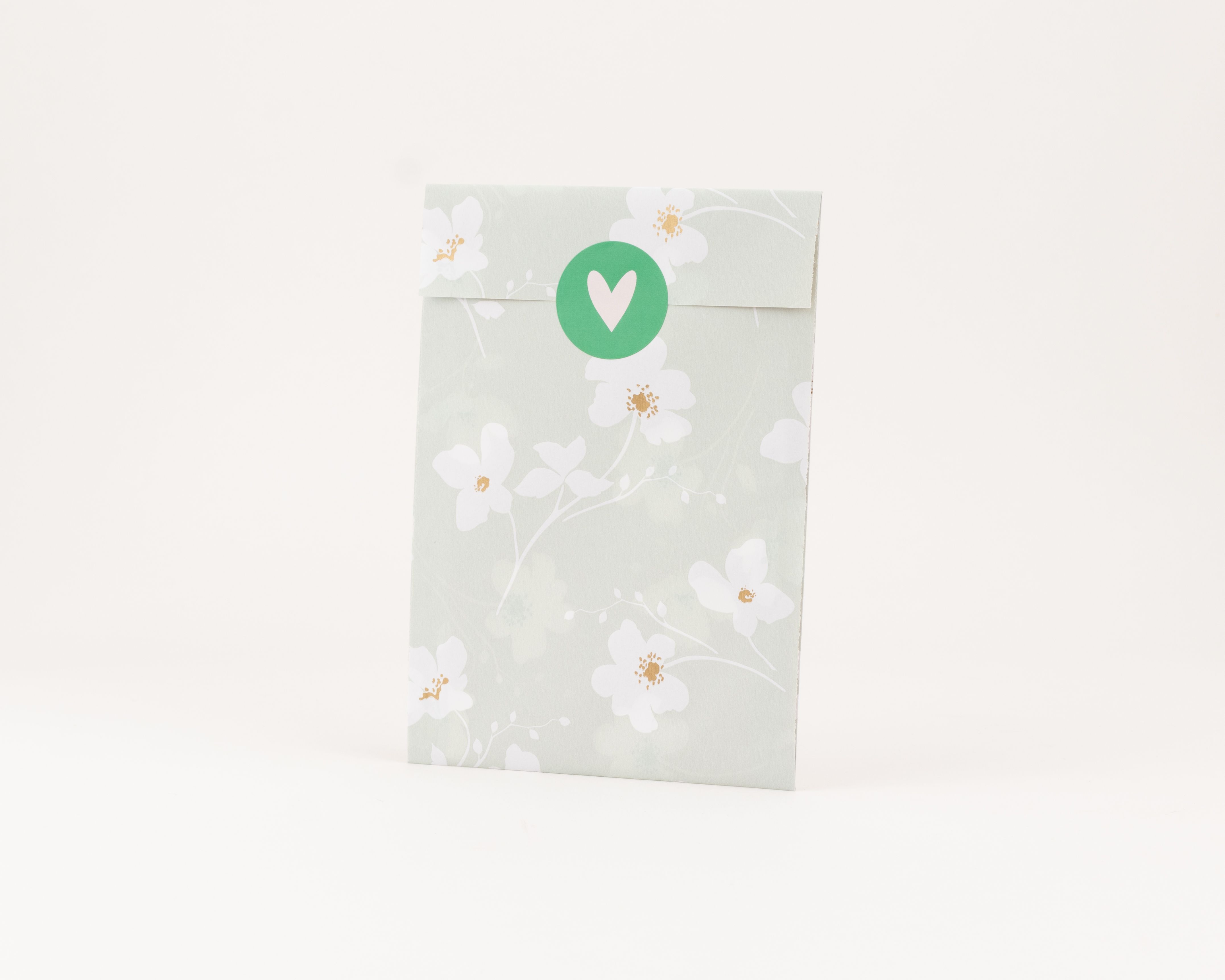 Flachbeutel salbeigrün mit Wiesenblüte-Muster, weissen Blüten mit Goldeffekt, grünem Herz-Sticker und weisser Innenseite