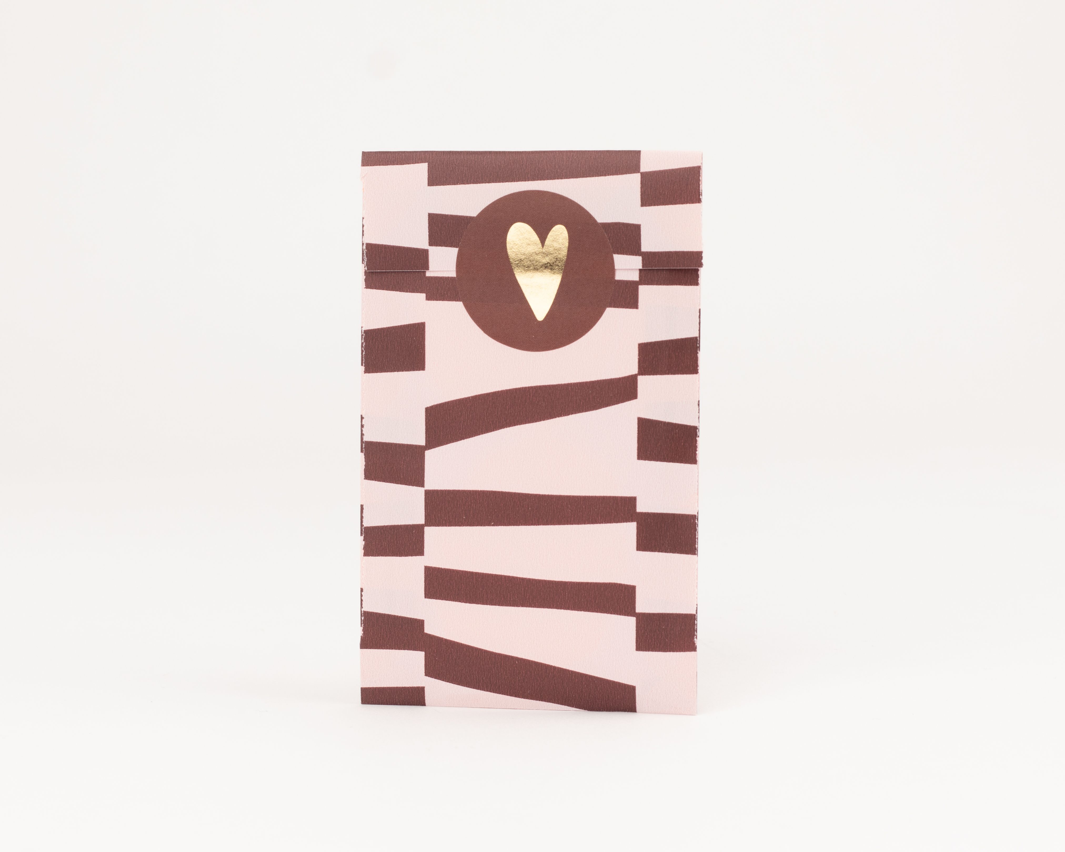 Flachbeutel mit einem Muster aus dicken, unregelmäßigen Streifen in Bordeaux und Rosa. Auf der Innenseite befindet sich ein bordeauxfarbener Kreis mit goldenem Herz