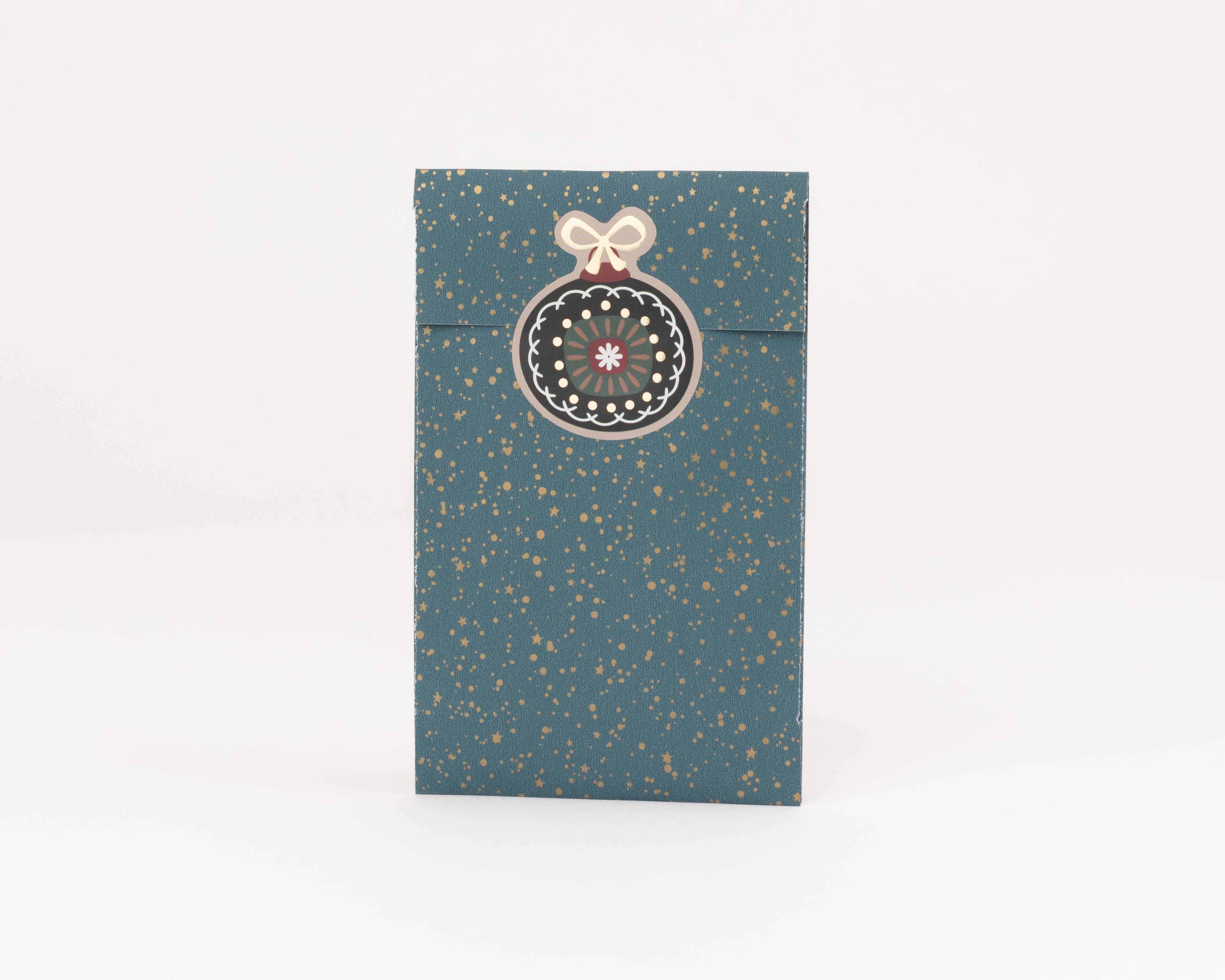 Flachbeutel in Petrolfarbe mit goldenen Sternen und Punkten, verziert mit einem dekorativen Weihnachtskugel-Sticker und Schleife