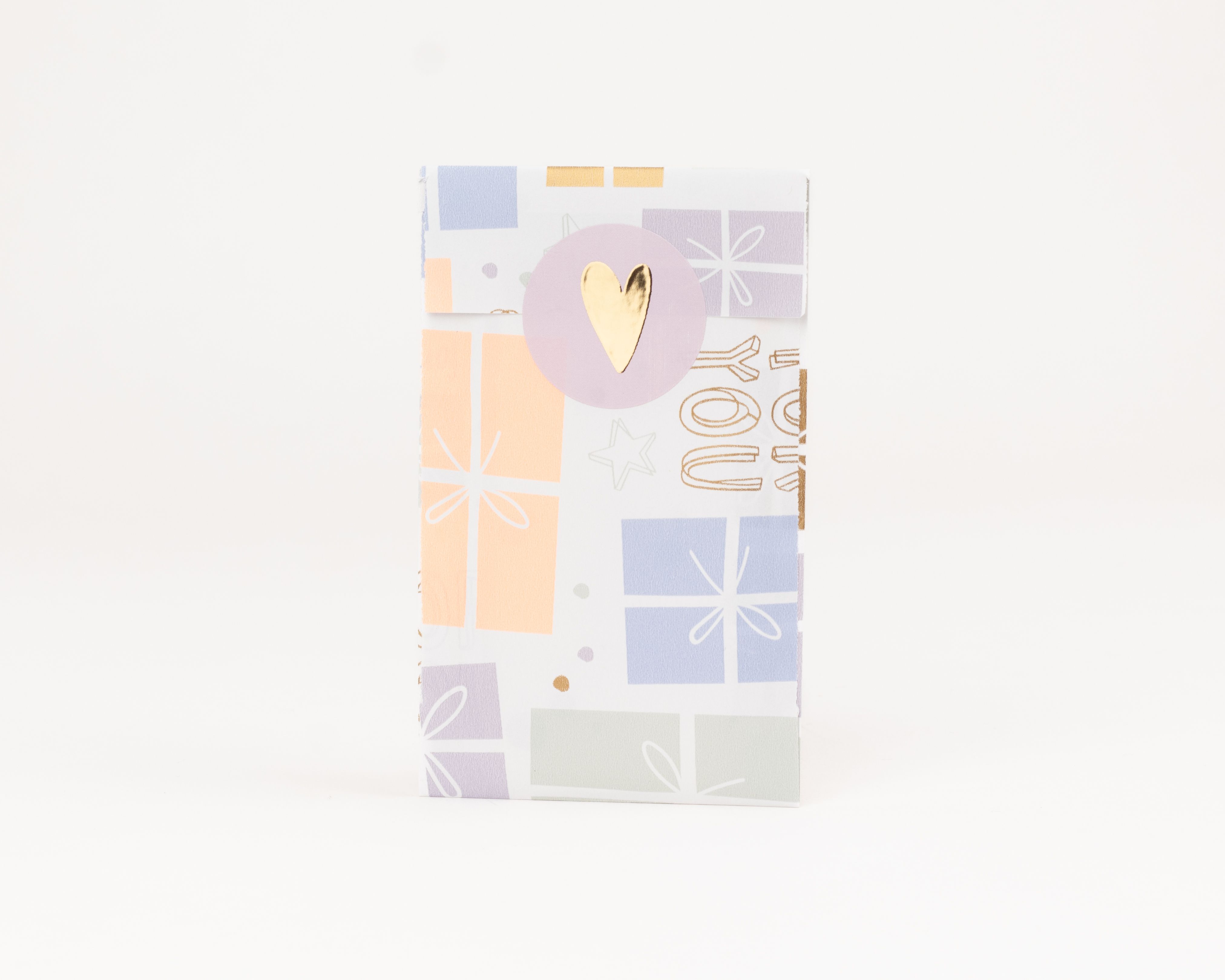 Flachbeutel mit pastellfarbenem Geschenkemuster auf weißem Grund und goldenen Details. Die helllila Innenseite ist mit einem goldenen Herz verschlossen