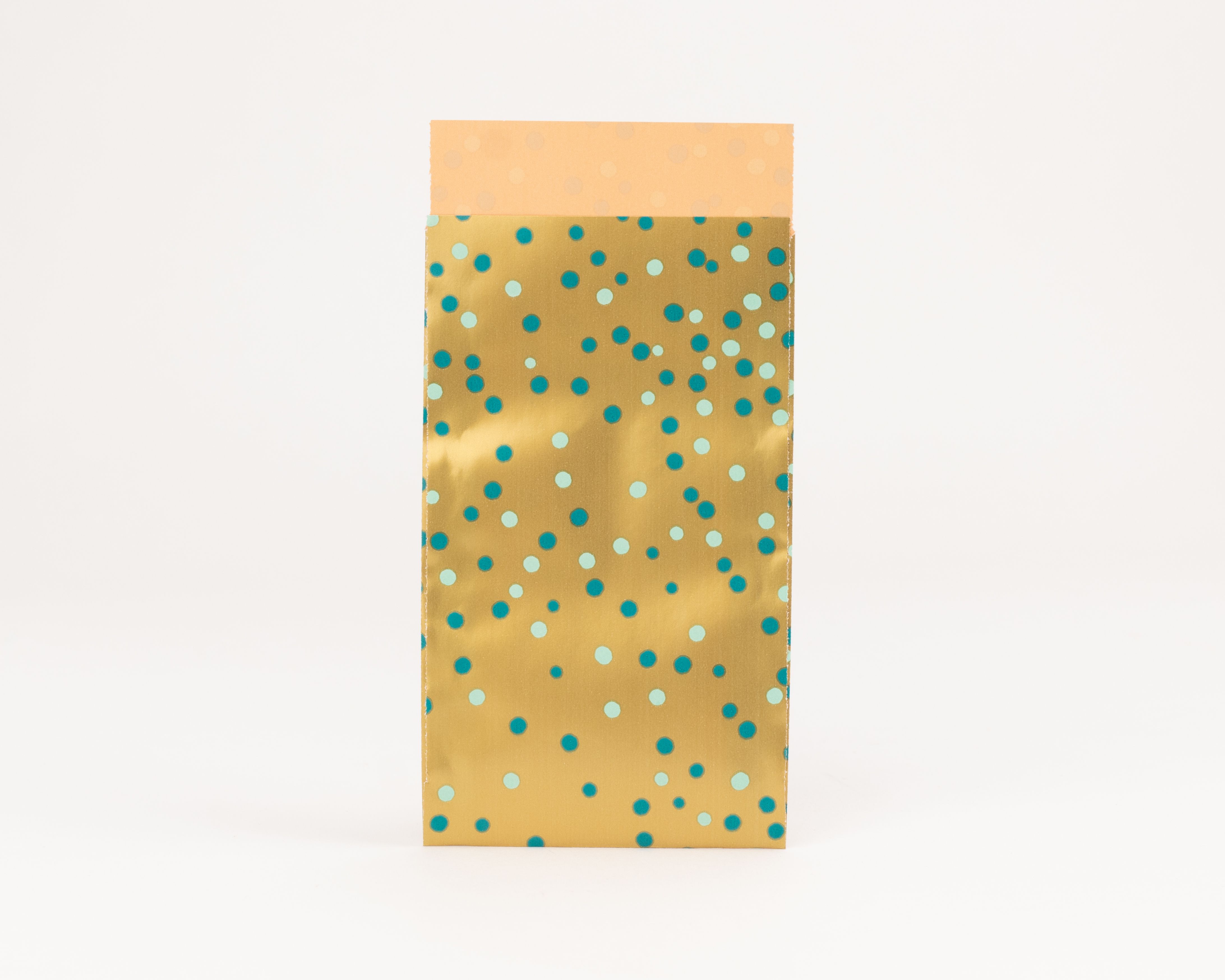 Flachbeutel mit goldenem Design und blauen Konfetti-Punkten, deren Innenseite einfarbig hellorange ist.