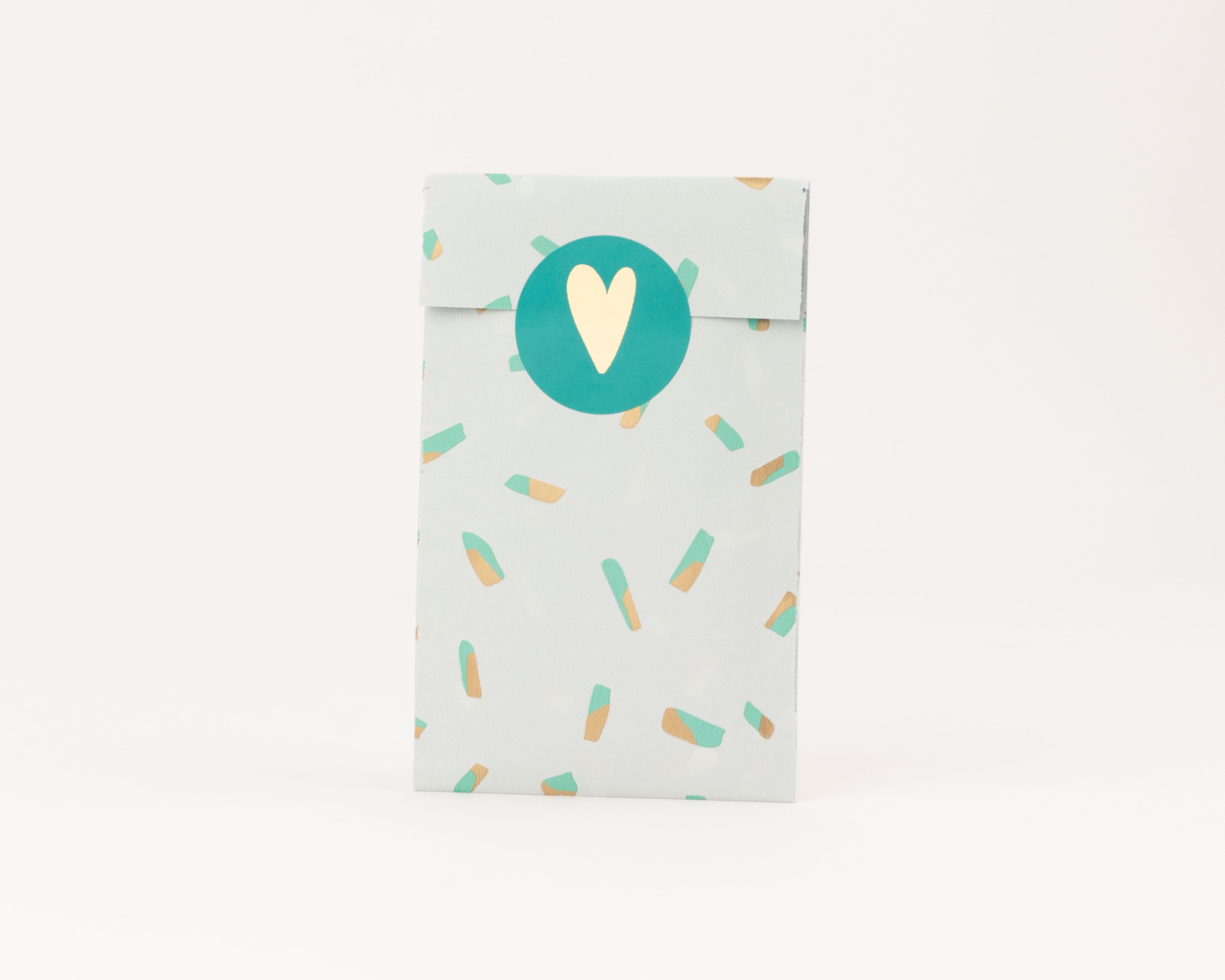 Flachbeutel in Salbeigrün mit einem Sprenkelmuster in Türkis und Gold mit Goldeffekt, verschlossen mit einem türkis-goldenen Herz-Aufkleber