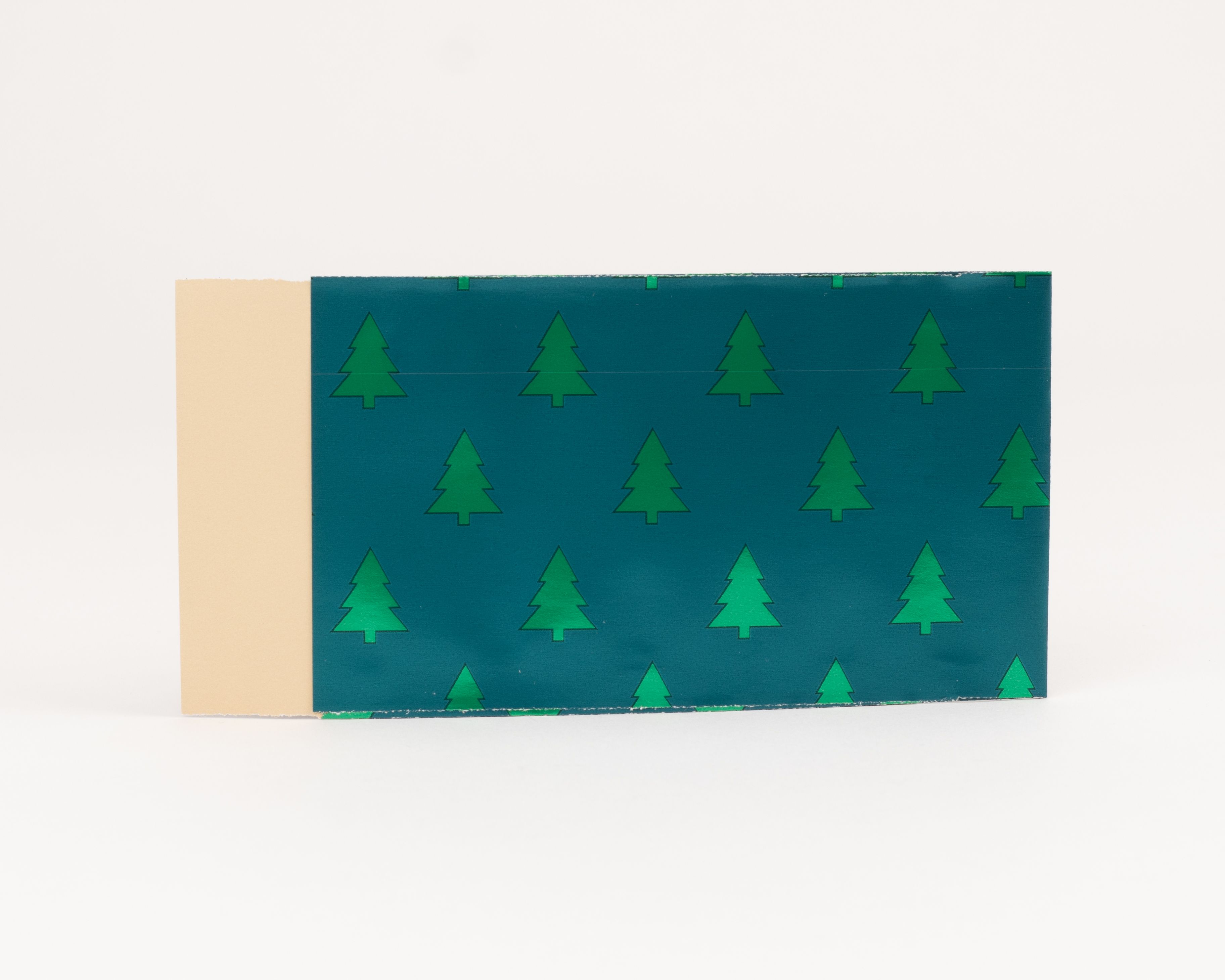 Flachbeutel mit dunkelgrüner Außenseite und wiederholtem Muster aus hellgrünen Tannenbäumen, die Innenseite ist hellbeige