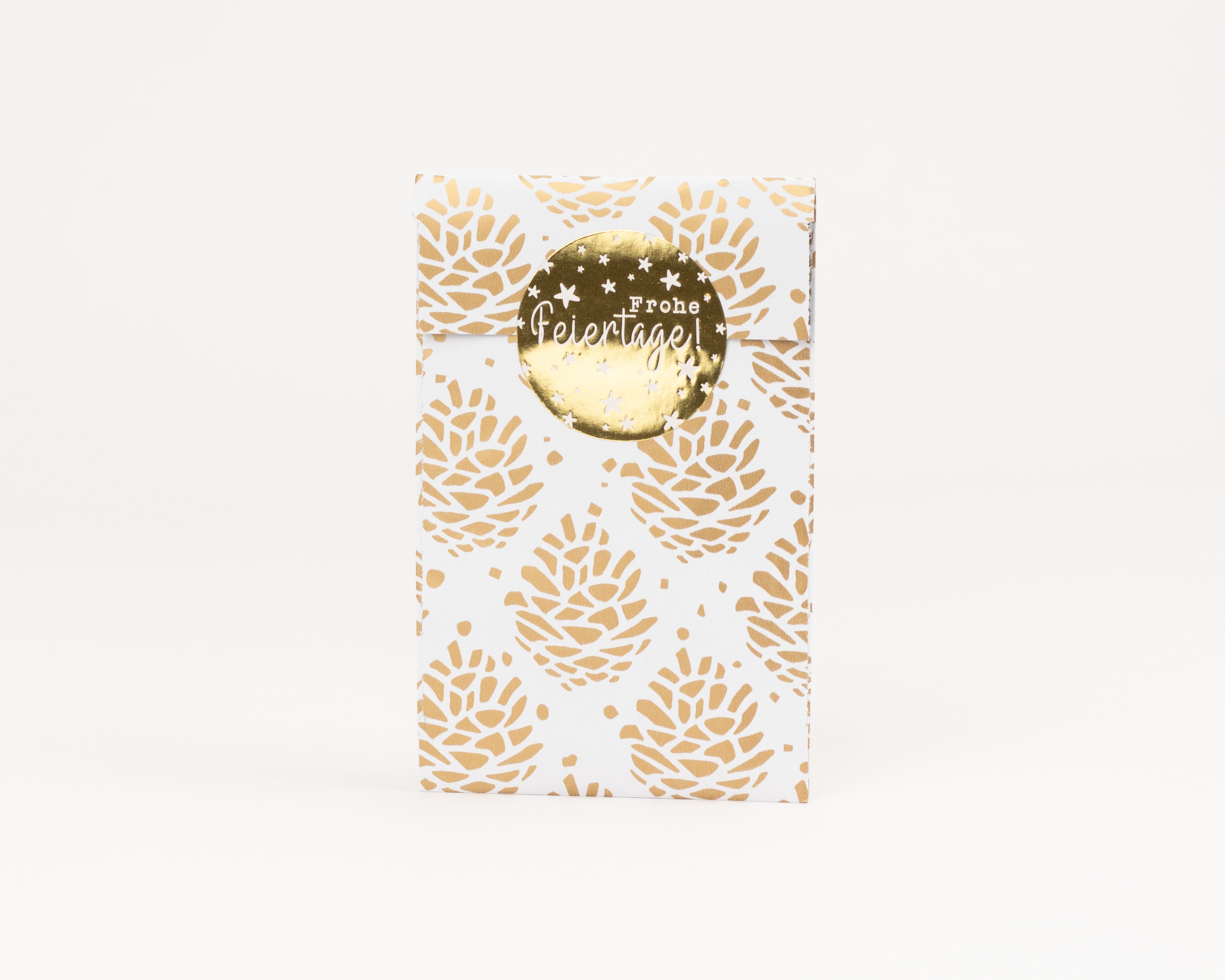 Flachbeutel mit einem durchgängigen goldenen Tannenzapfenmuster auf weißem Grund, verschlossen mit einem runden goldenen Aufkleber