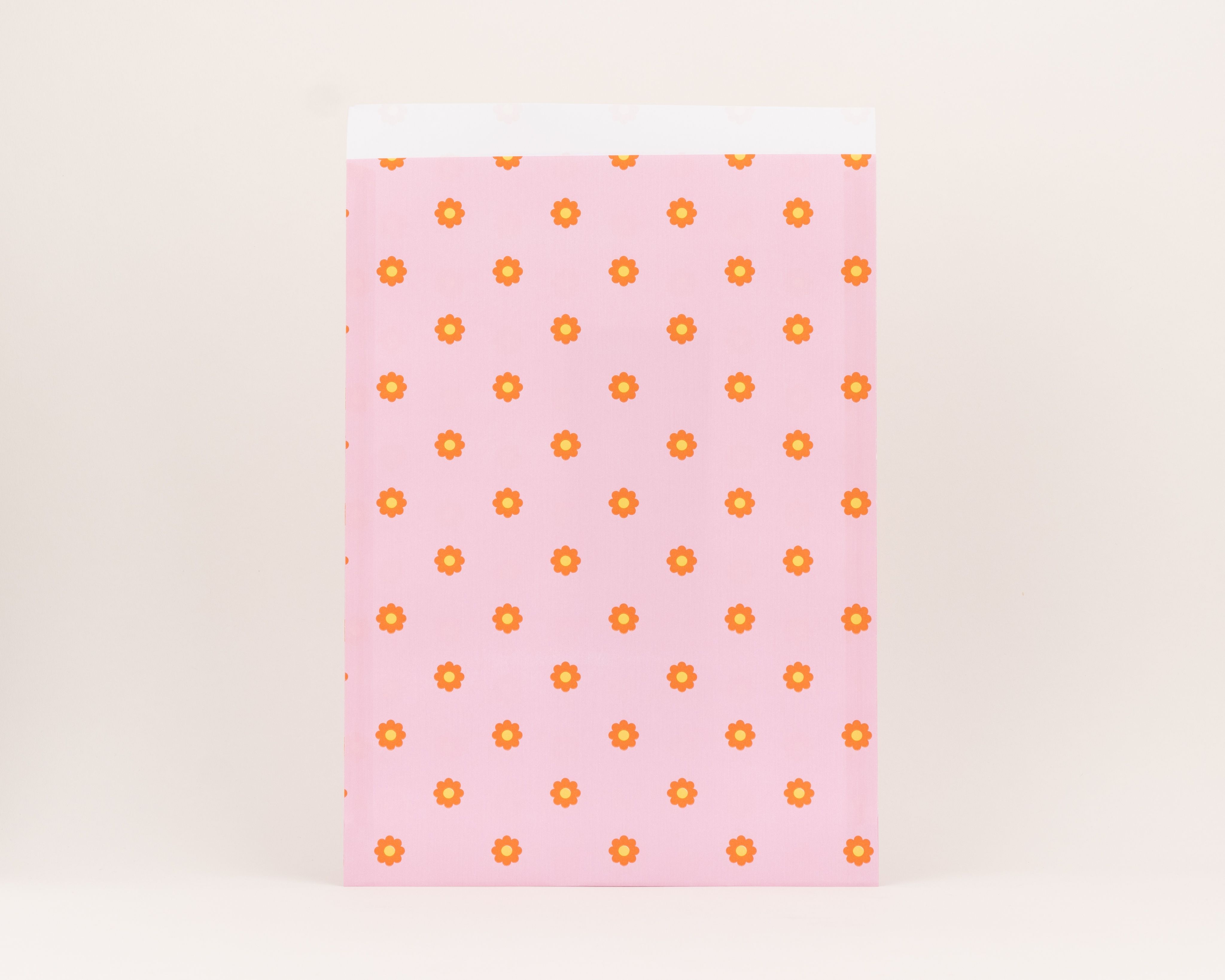 Flachbeutel in Pink mit einem Muster aus orange-gelben Gänseblümchen und weisser Innenseite