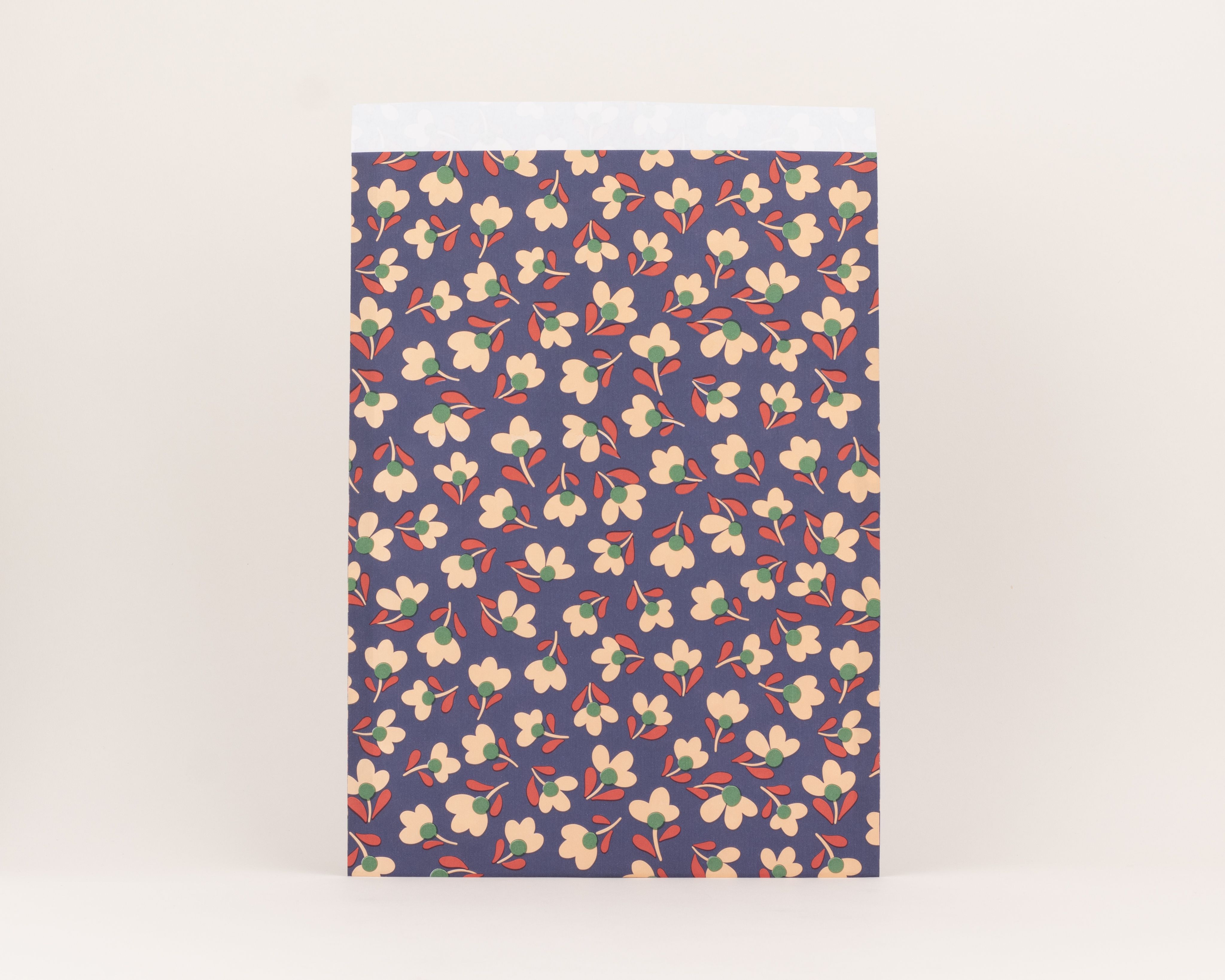 Flachbeutel mit dunkelblauem Grundmuster, verziert mit beigefarbenen Blüten, grünen Blütenmitten und roten Blättern, innen beige