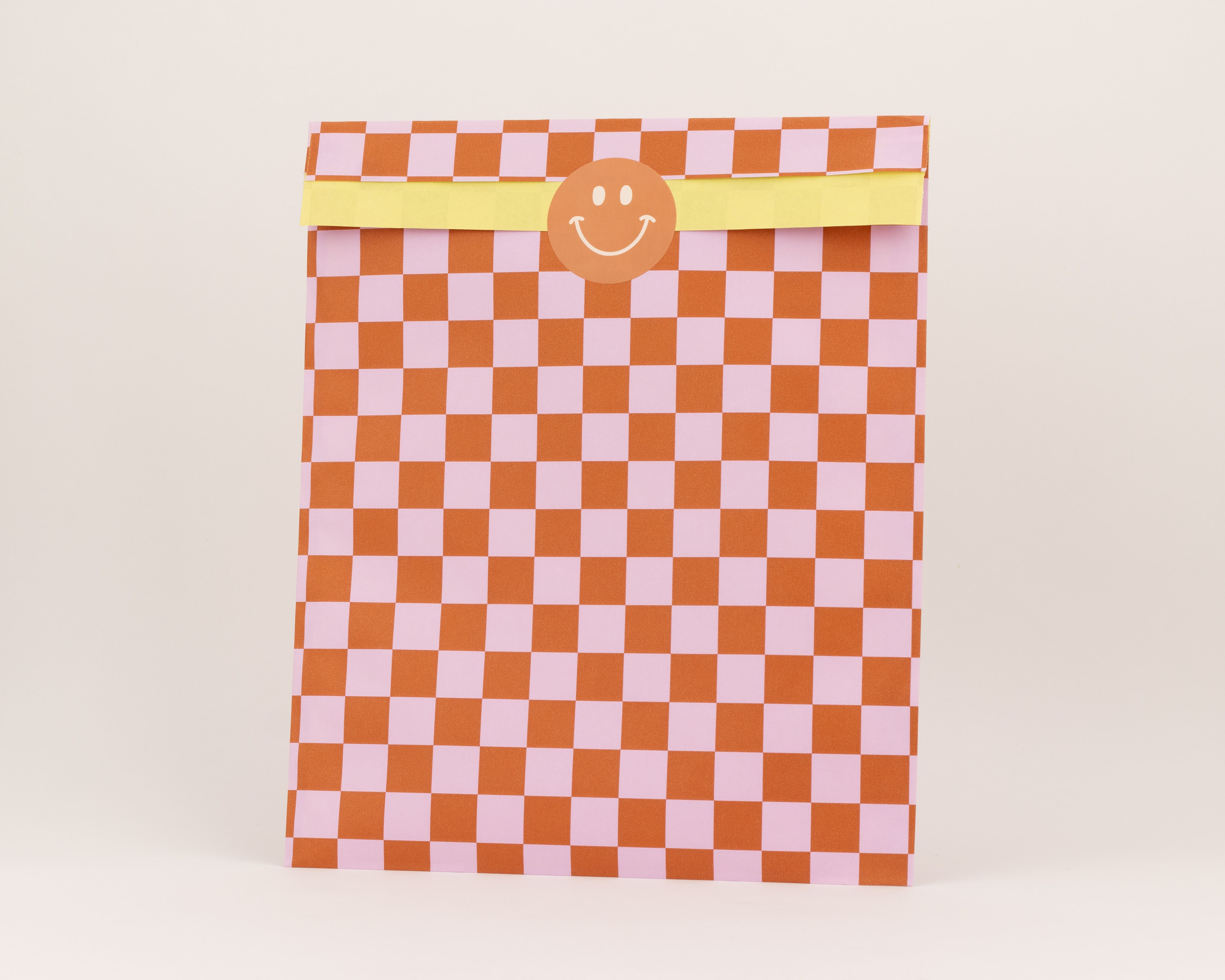 Flachbeutel mit Schachbrettmuster in Zimt und Rosa, die Innenseite des Beutels zeigt einen gelben Farbton