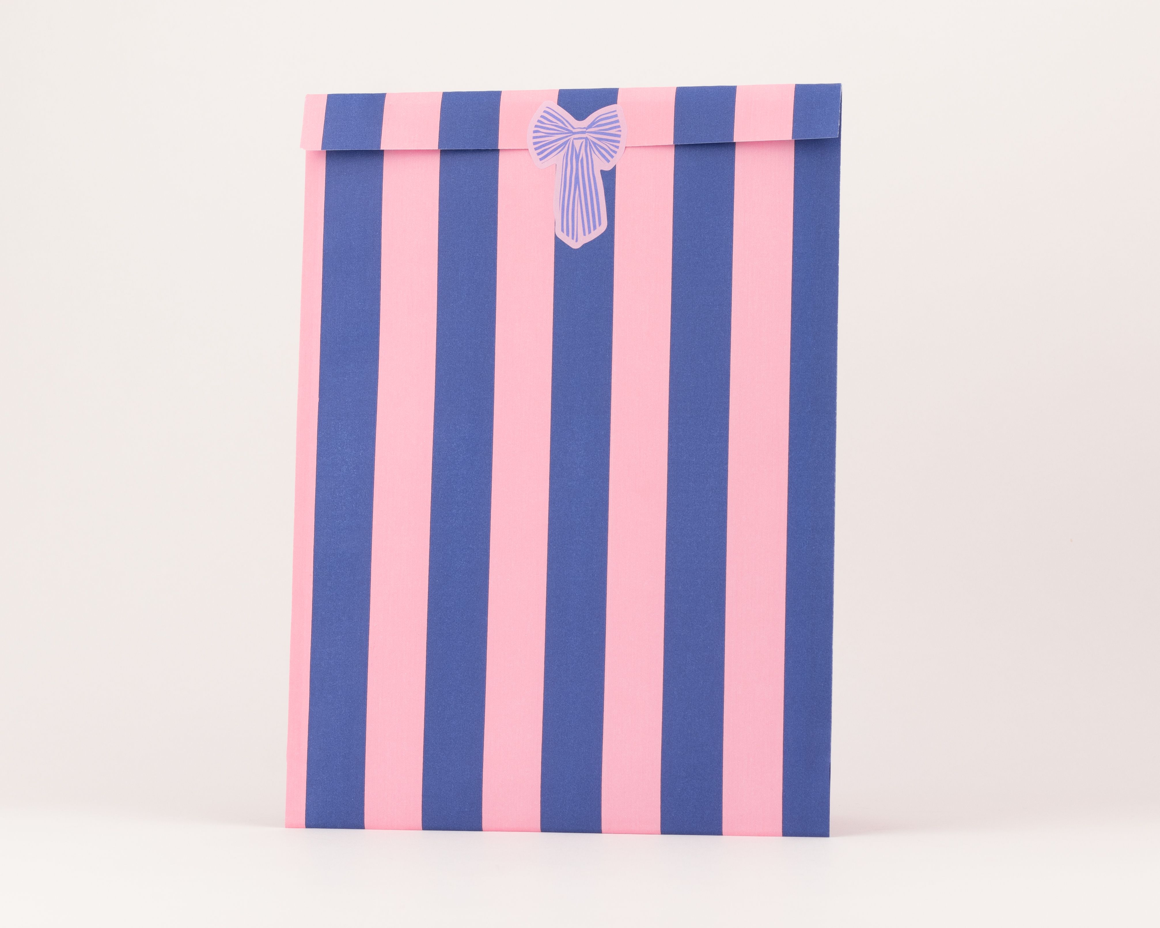 Flachbeutel mit vertikalen Streifen in Blau und Pink, verziert mit einer kleinen Schleife und weißer Innenseite