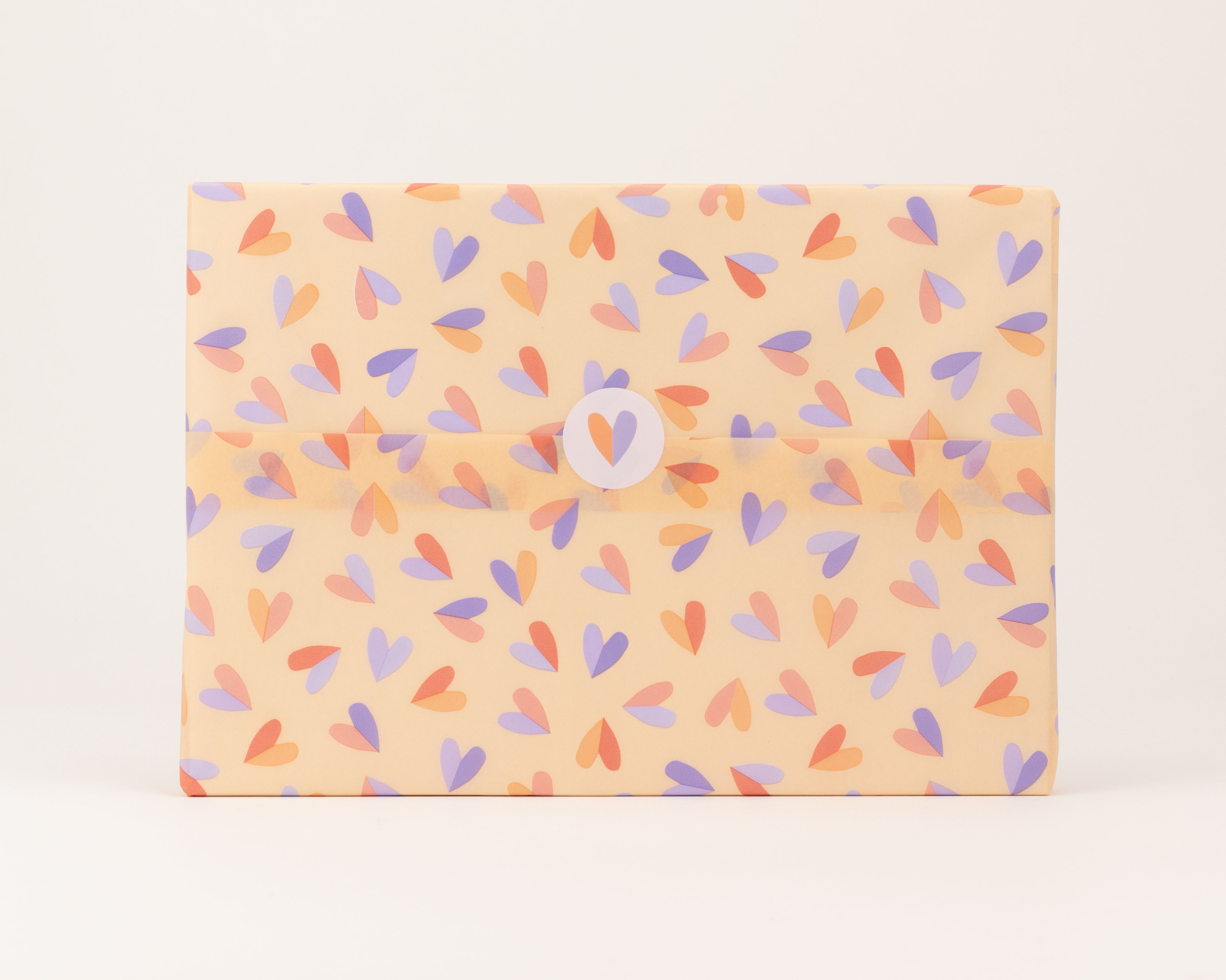 Seidenpapier mit einem Herzmuster auf aprikosefarbenem Grund, wobei die Herzen in lila und orange gehalten sind