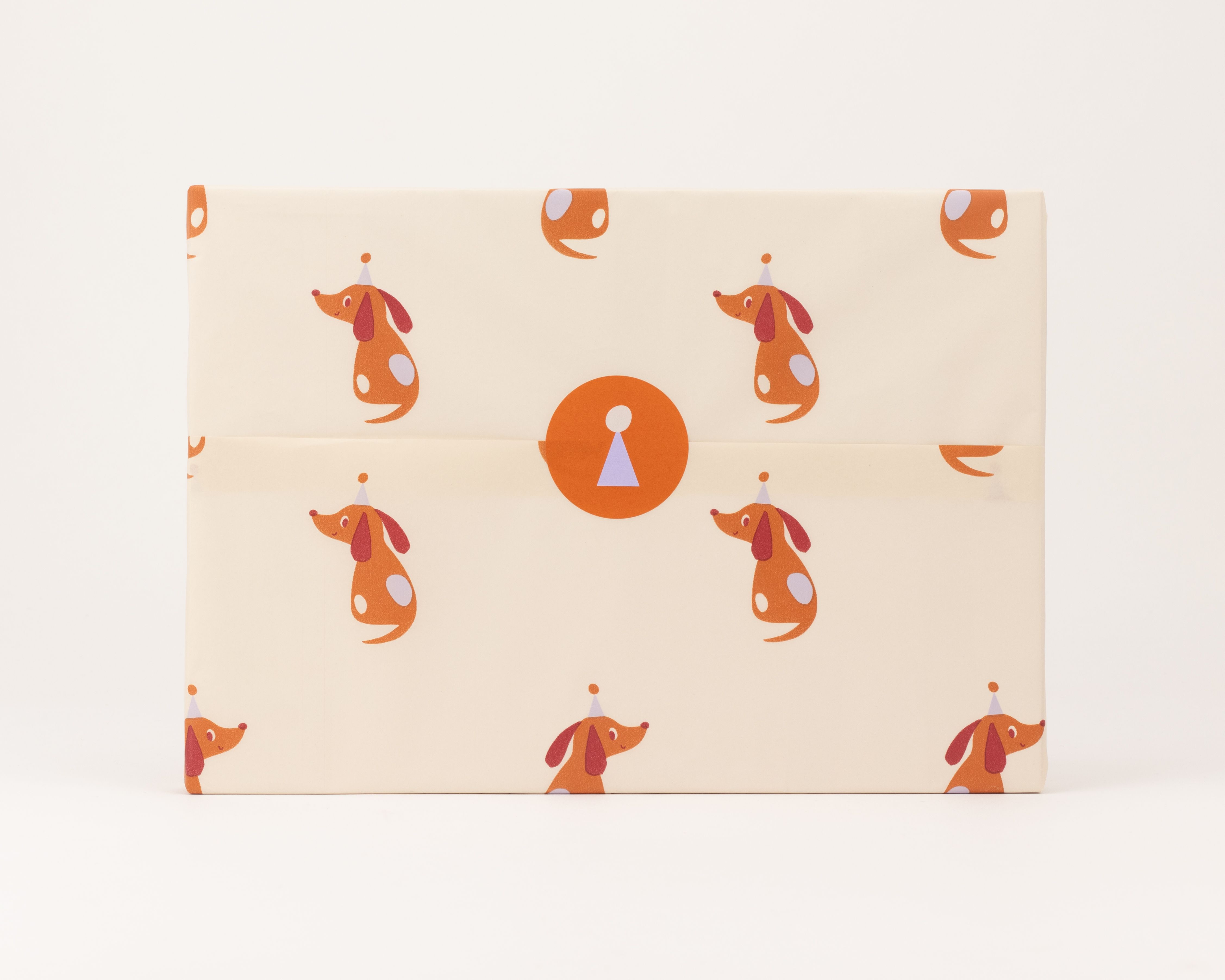 Seidenpapier in Beige mit Party Dackel Muster in Braun und Flieder. Darauf ein brauner runder Aufkleber mit Flieder-Symbol