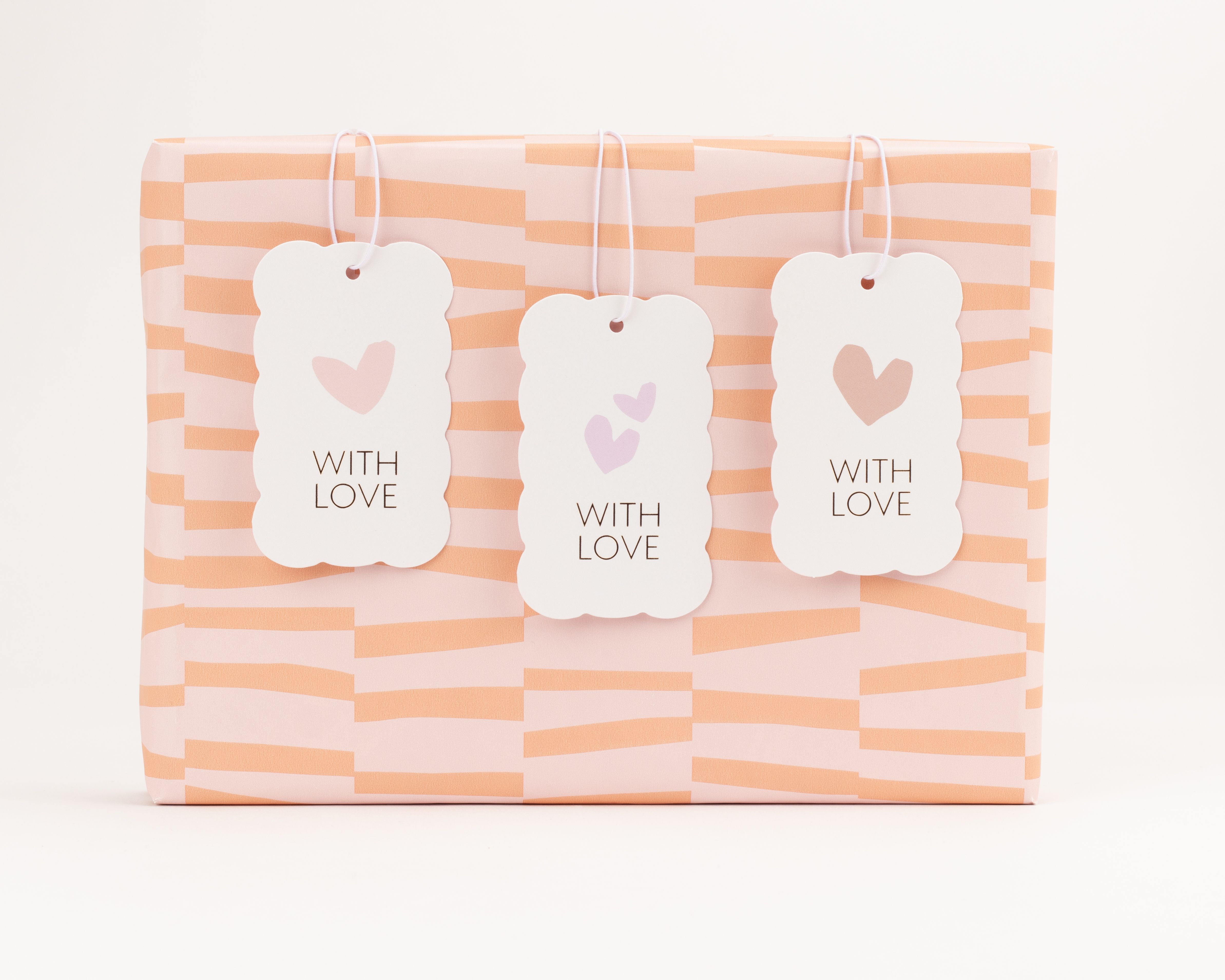 Geschenkanhänger-Set mit drei wolkenförmigen weissen Anhängern, jeweils mit einem Herzen und dem Schriftzug With Love in Pastellfarben