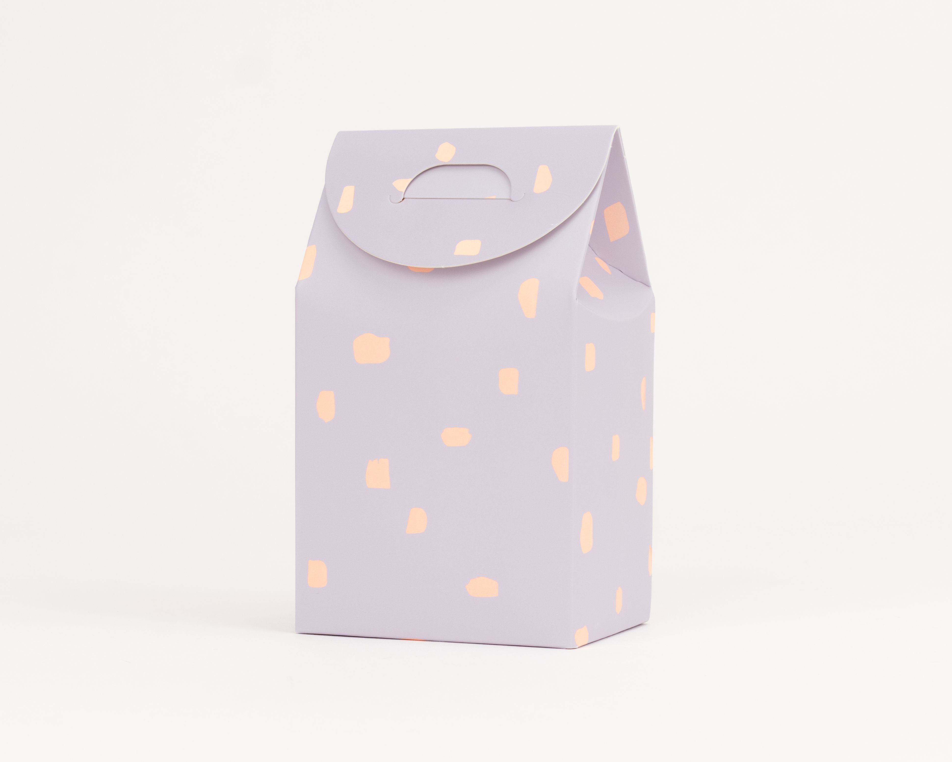 Geschenkboxen in Helllila mit unregelmäßigen orangefarbenen Tupfen und integriertem Tragegriff an der Oberseite