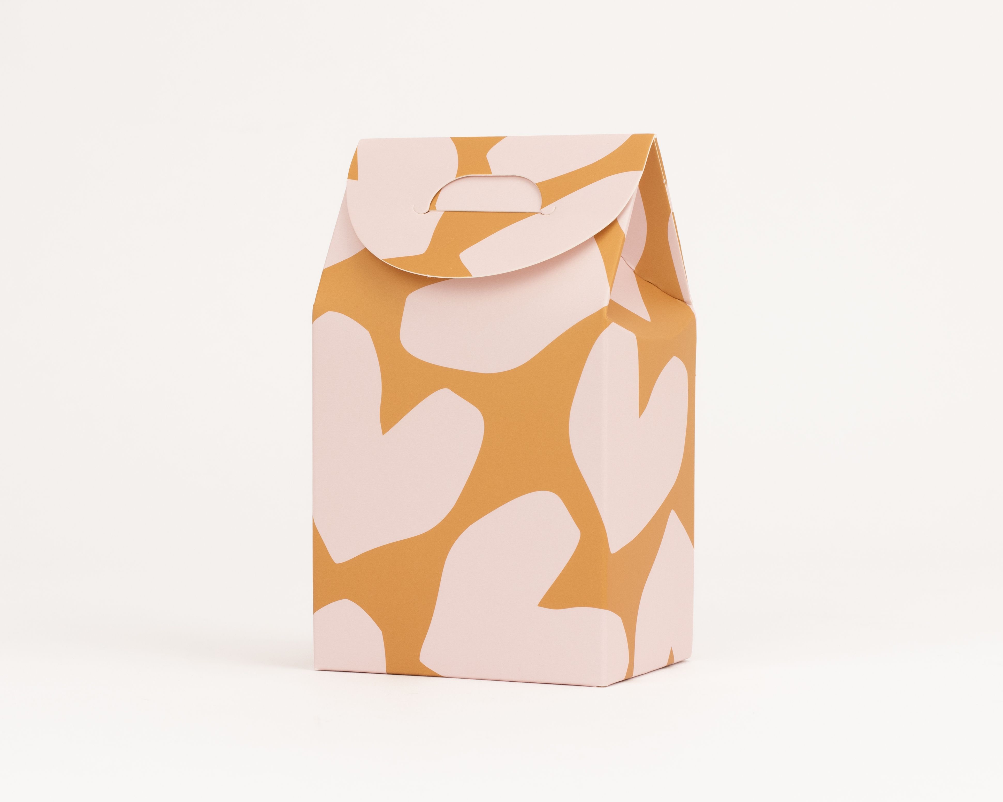 Geschenkboxen in rechteckiger Form mit hellrosa Herz-Muster auf ockerfarbenem Hintergrund und integriertem Griff